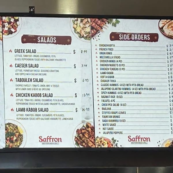 A Saffron restaurant menu board displays various kabob plates, salads, side orders, and catering options.